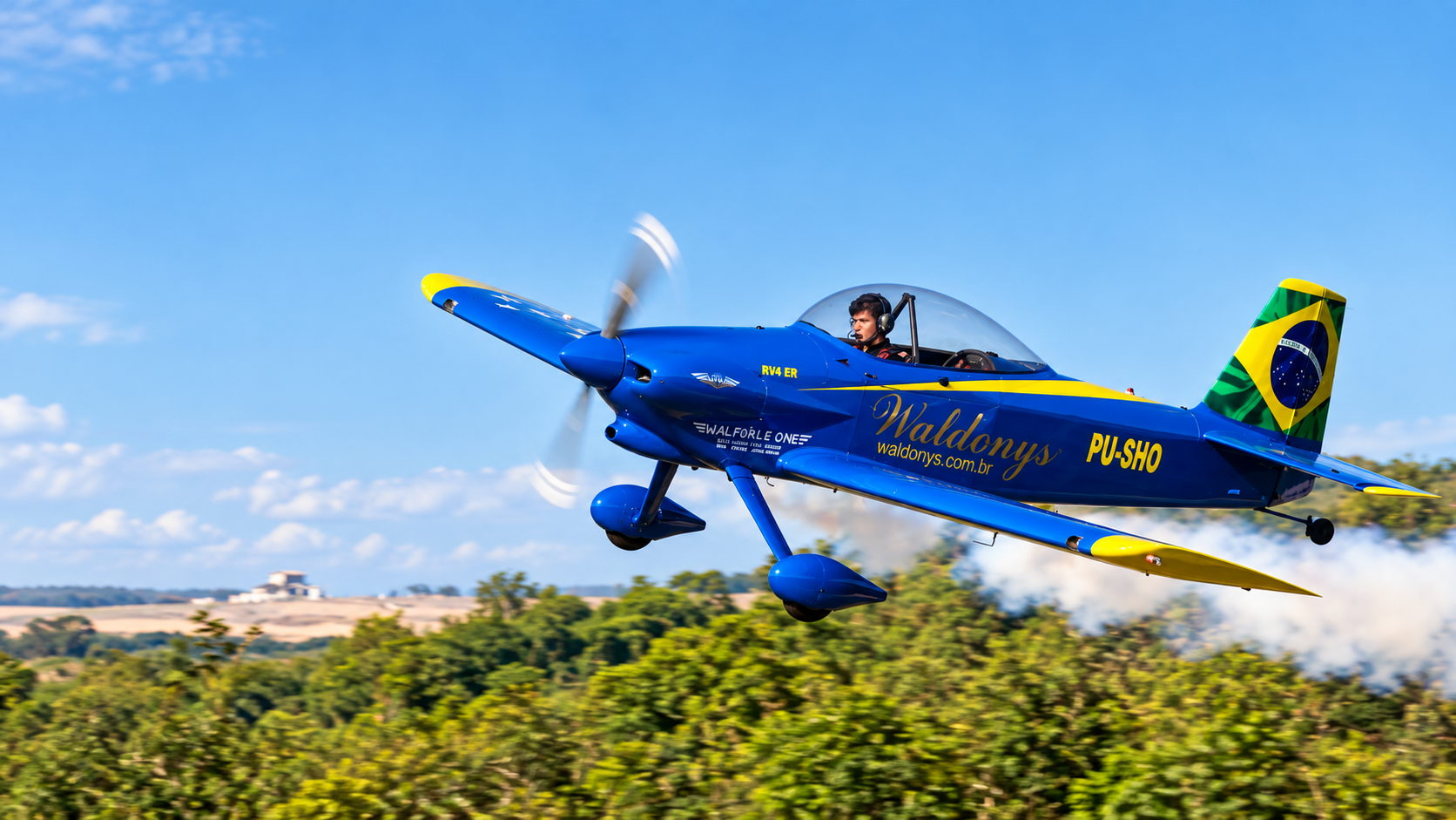 Avião azul de Waldonys em voo sobre a paisagem brasileira.
